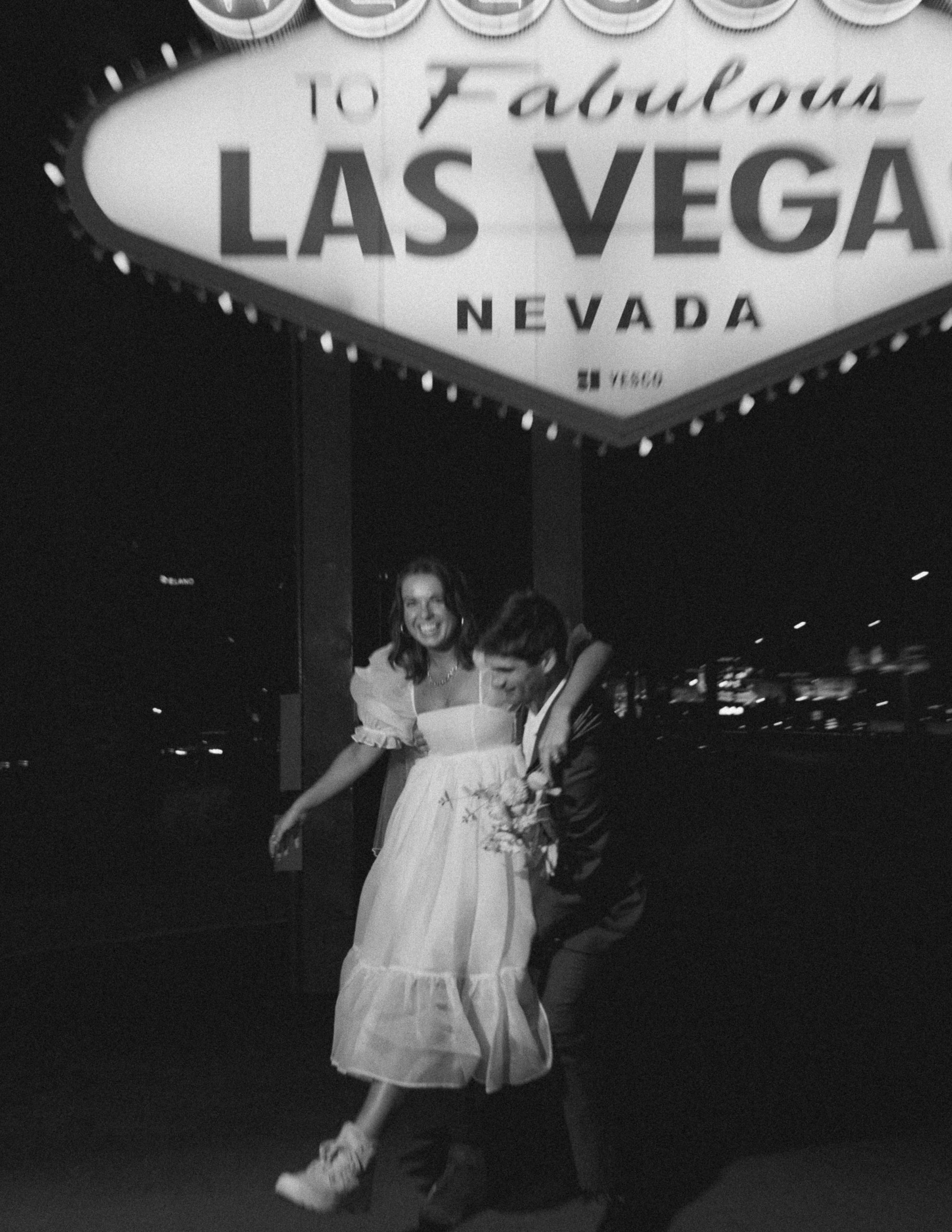 couple pose in front of vegas sign