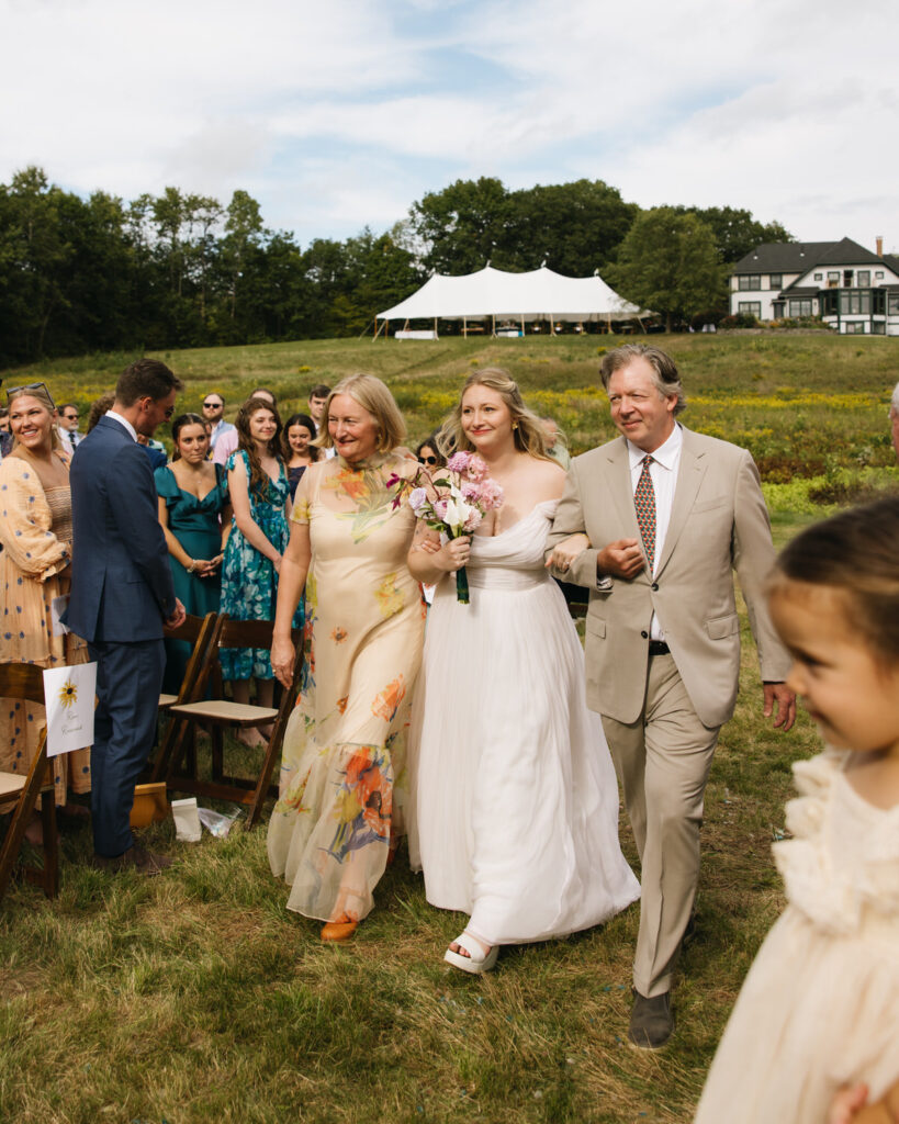 The bride and her parents walk down the aisle in this Maine wedding