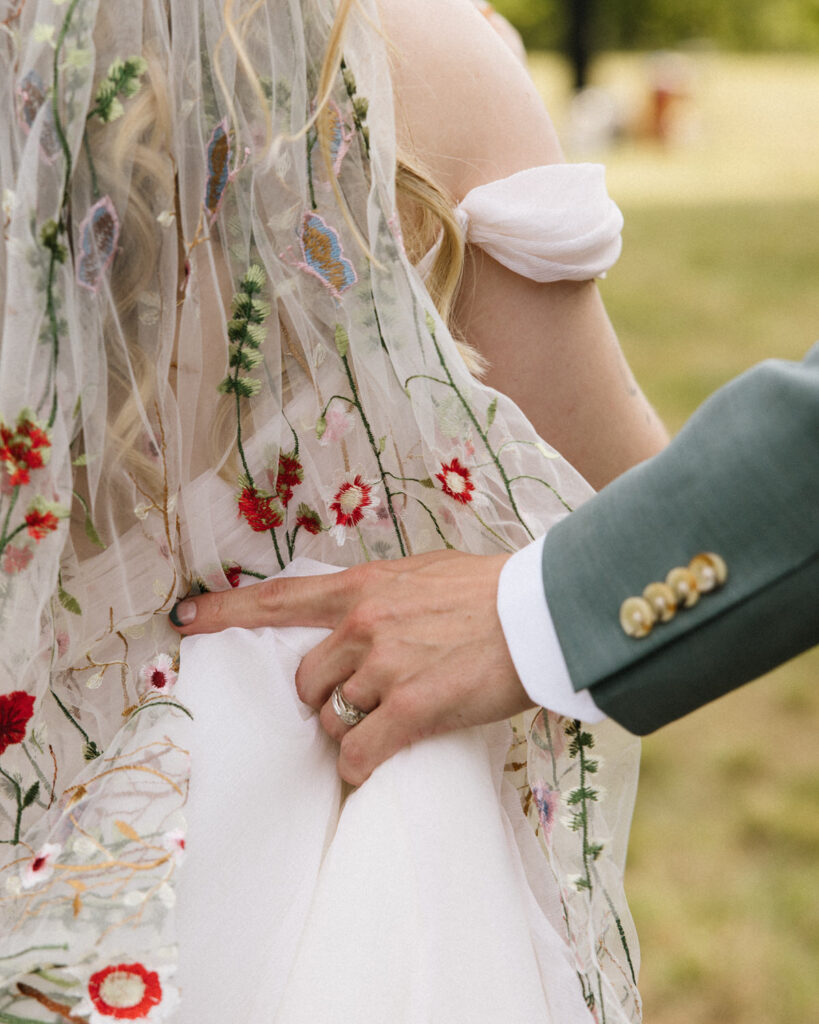 Groom holds brides dress as they walk to their cocktail hour