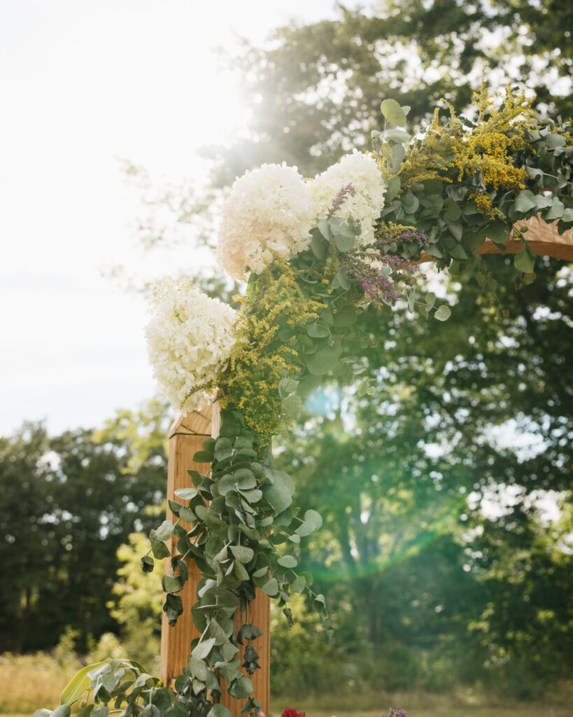 Floral arch install over the ceremony space at a wedding in Maine