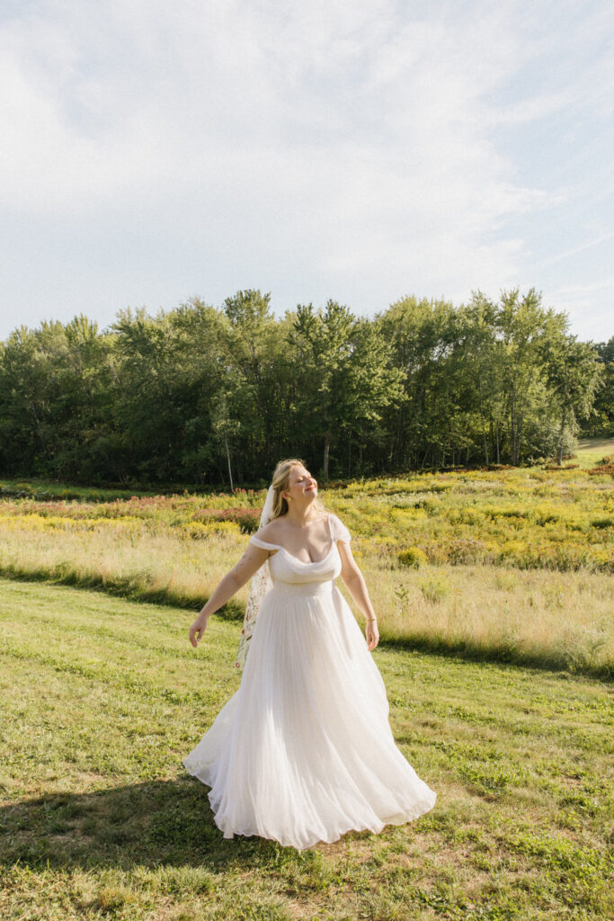 Bride frolics in meadow in valley of wedding venue