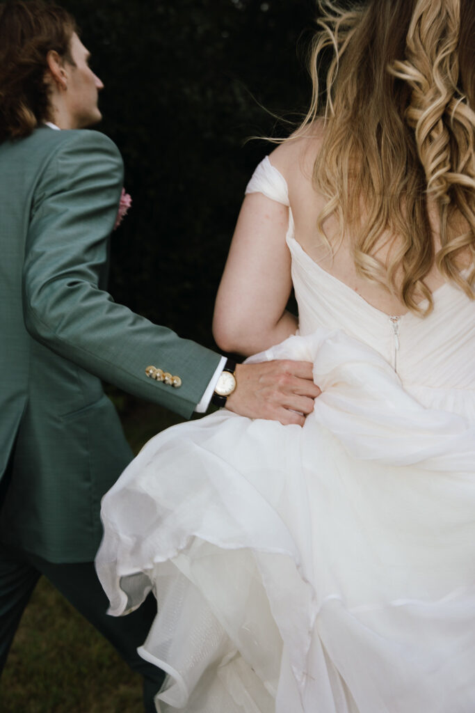 Intimate detail of groom holding brides dress on the way to take portraits